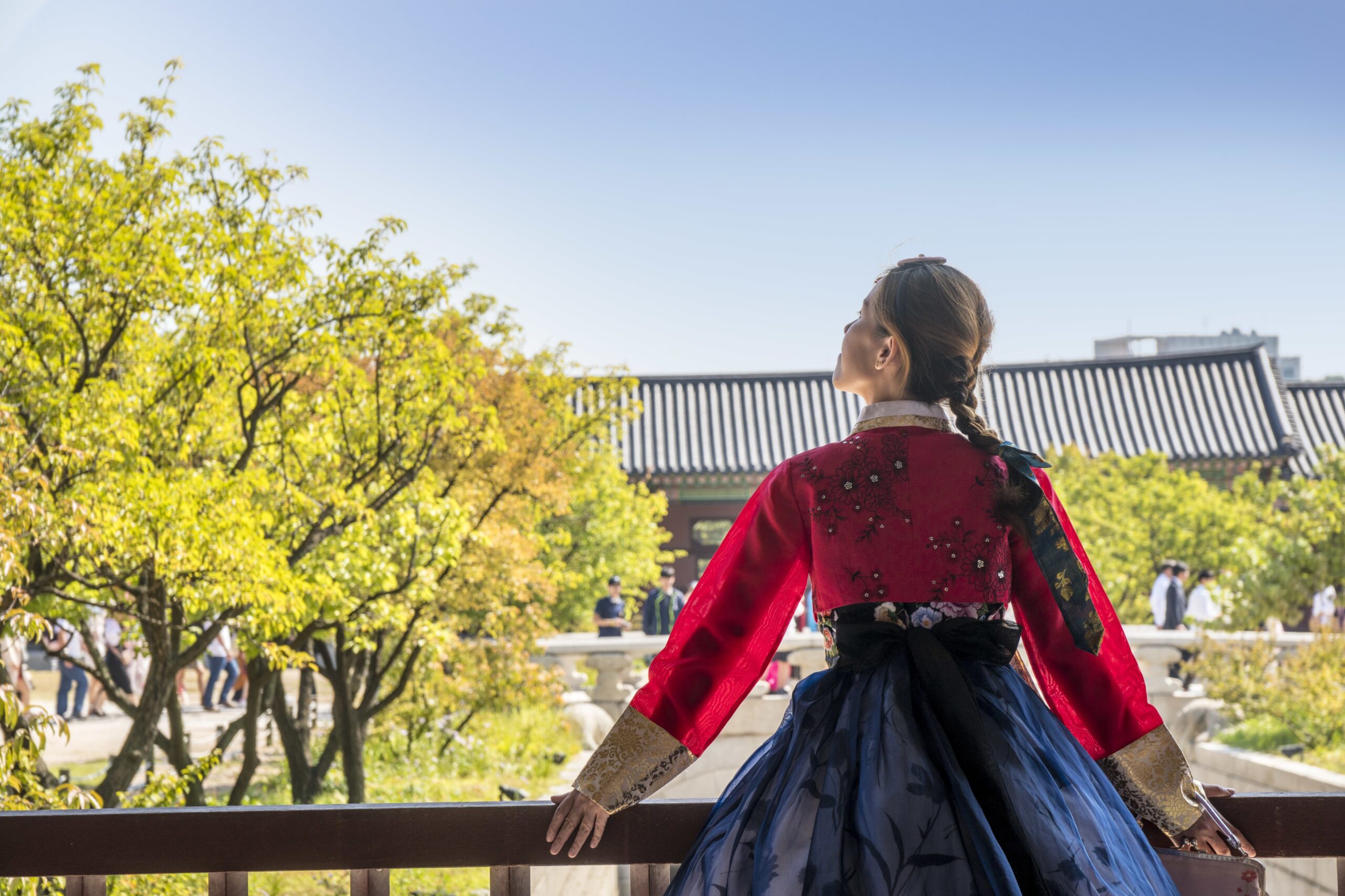 Woman in traditional Korean clothing looking up at the sky